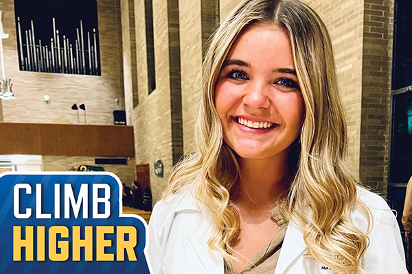 Mount St. Joseph student Emily in white nursing coat in mater dei chapel smiling.