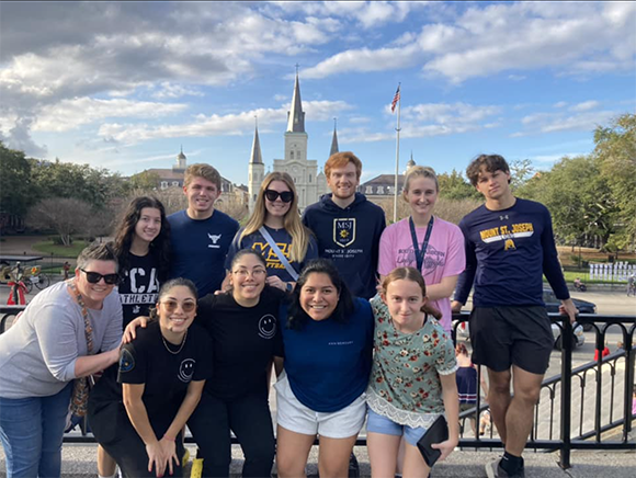 Group of students with Mount wear lean against a gate with a building in the background