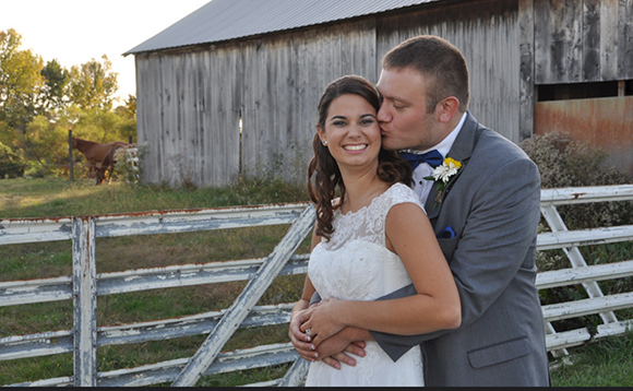 couple standing by barn 