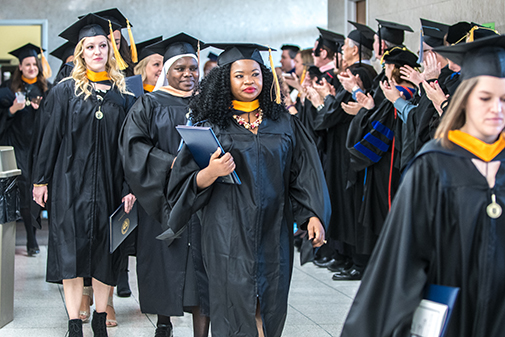 faculty clapping for newly-graduated students walking by.