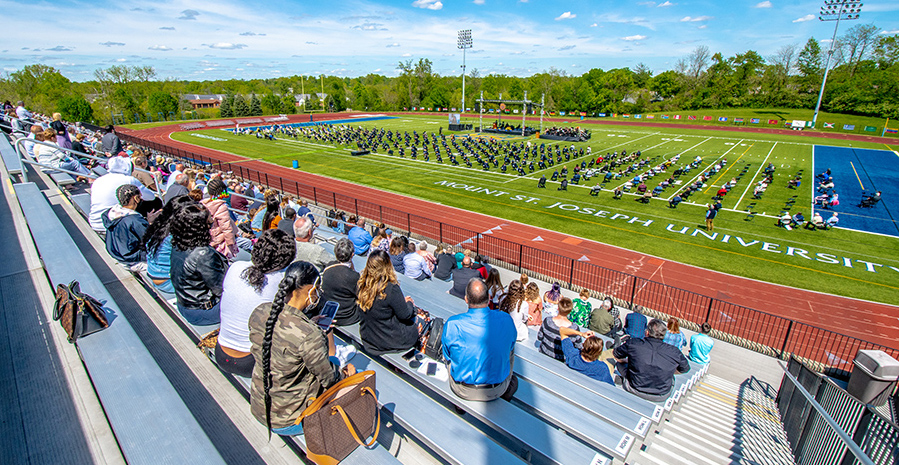 people sitting in stands at schueler field 