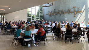 people gathered in university theatre lobby at tables for event.