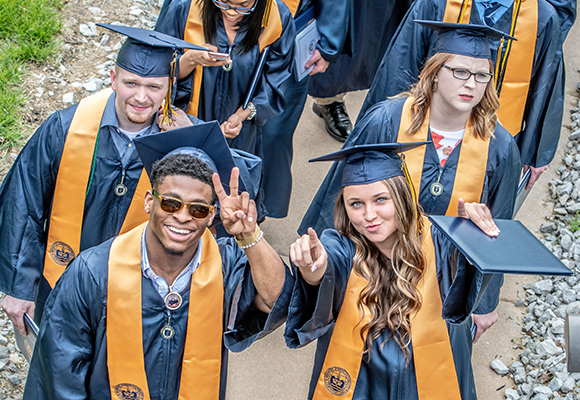 students walking and smiling at camera after commencement ceremony