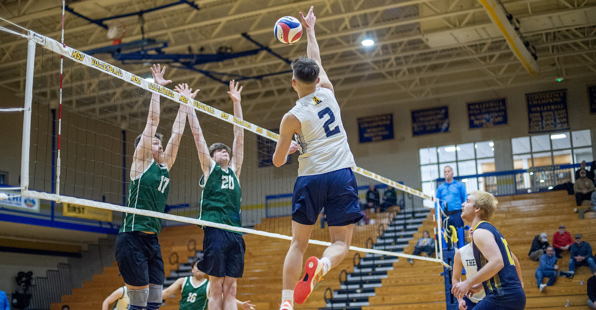 male volleyball player spiking the ball over the net