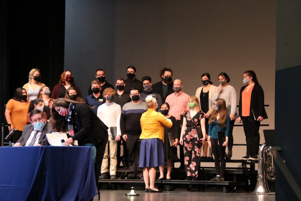 university singers singing national anthem in theatre.