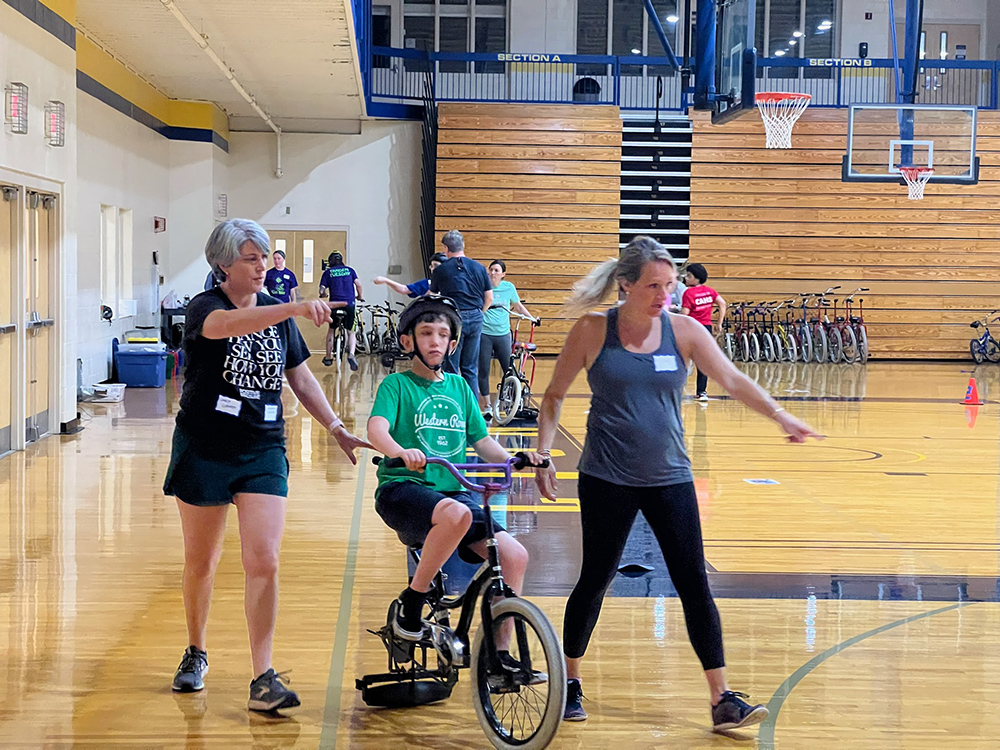 child learning to ride a bike in MSJ Harrington Gym.