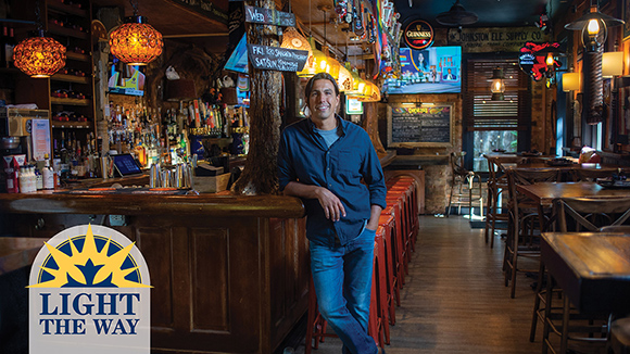 Mount St. Joseph alumnus juan imeroni standing next to bar at Che's in Over the Rhine. 