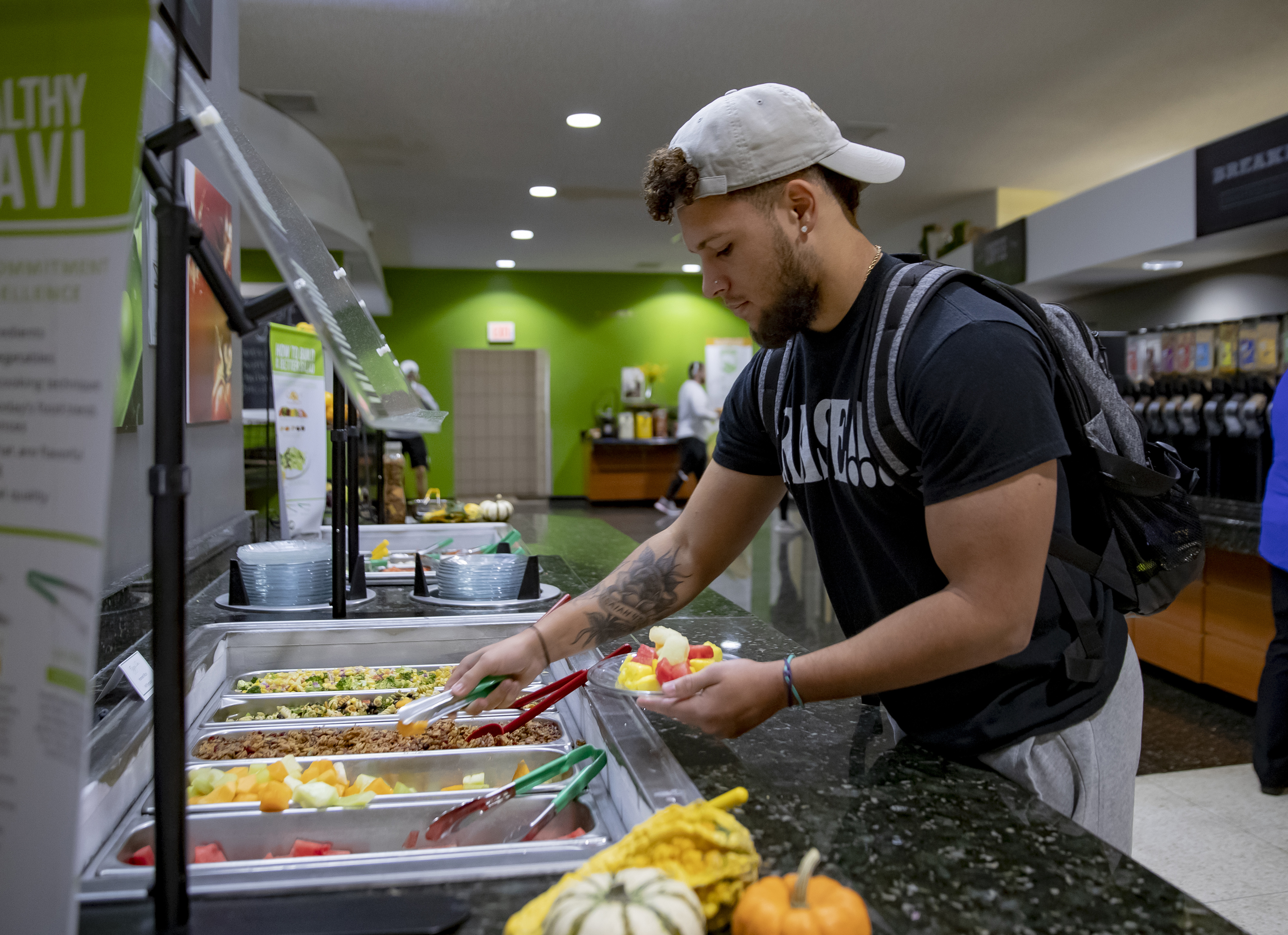 males student grabbing food with tongs at the salad bar